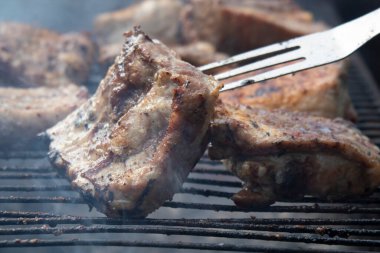 Doğada doyurucu bir öğle yemeği hazırlıyoruz. Domuz pirzolası kömürde kızartılır. Bir çatalla, et parçalarını çevirin ki eşit derecede kızarsınlar..