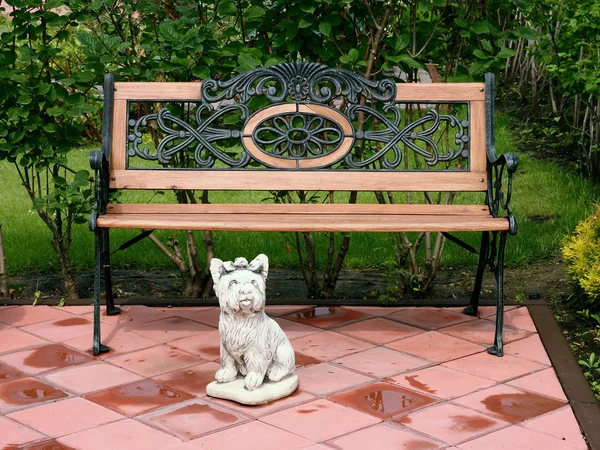 Un banco y una escultura de un perro pequeño en el parque . —  Fotos de Stock