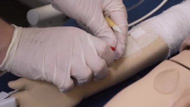 Yakın plan, bir periferik venöz sonda simulasyon bebek eline takılır.