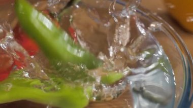 Rajasthani koca kırmızı ve yeşil biberleri bir kase suya doldurur. Baharatlı yemek. Ahşap masadaki şeffaf cam kasede yeşil saplı sıcak ve baharatlı Mirchi 'nin yakın plan çekimi.