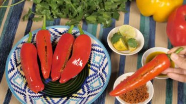 Kadın, kırmızı biber dolması ve diğer biberleri masaya koyuyor. Bir kase Masala, limon dilimleri, hardal yağı ve Hint Mirchi Achaar 'lı kişniş.