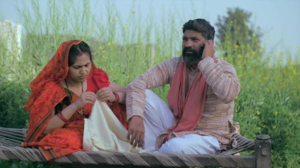 Een Dorpshuisvrouw Naait Kleren Terwijl Haar Man Aan Telefoon Indiase — Stockvideo