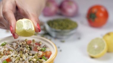 Kadın elleri taze limon suyunu soğanla karıştırılmış lahanalara sıkıyor. Moong Dal, soğan, domates ve nohut karışımlı limon dilimlerinin yakın plan çekimi.