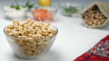 Kurutulmuş çiğ bezelyeler beyaz bir masanın üzerine düştü. Sağlıklı yiyecekler. Şeffaf bir kaseye yerleştirilmiş Bengal gramının yakından çekimi - protein zengini vejetaryen diyeti