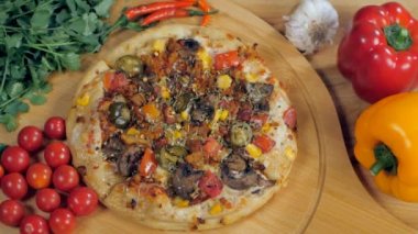 Yeni pişmiş pizzanın üzerine kırmızı biber taneleri düşüyor. Yanında mısır, peynir ve zeytin de var. Fesleğen yapraklı, kırmızı biberli, biberli ve sarımsaklı ev yapımı bir pizzanın yakın plan çekimi.