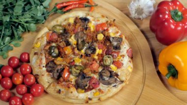 Mısır ve zeytinli vejetaryen pizzanın üzerine rendelenmiş peynir düşüyor. Lezzetli bir pizza, domates, dolmalık biber ve sarımsağın yakın plan çekimi.