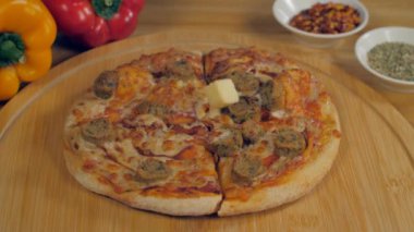 Lezzetli bir İtalyan pizzasının üzerine düşen küçük peynir küpleri - popüler atıştırmalıklar. Tahta bir masada kekikli, acılı ve dolmalık biberli leziz tavuk sosisli pizzanın yakın plan çekimi.