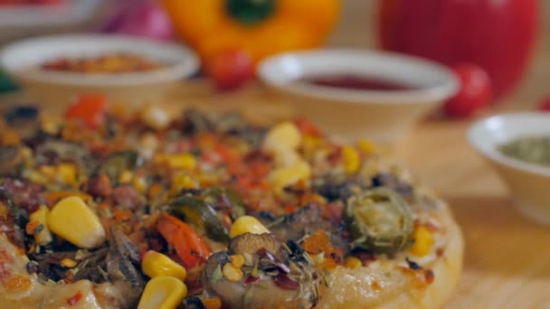 Sladké kukuřice padající na čerstvě upečenou domácí vegetariánskou pizzu - chutné jídlo. Celá pizza s chilli vločkami, rajčatovým kečupem a oreganem držená v rozmazaném pozadí