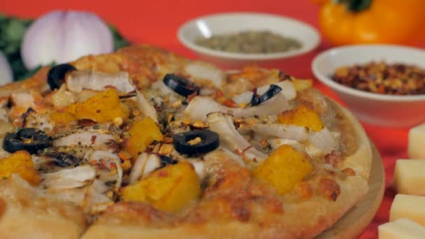 砕いた赤唐辛子とパンジャーピザの味付け イタリア料理 カラフルな背景の下に置かれたおいしい焼きピザの極端なクローズアップショット — ストック動画