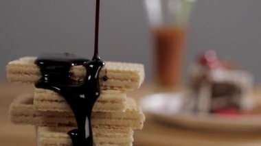 İnce bisküvi wafflelarının üzerine sıvı koyu çikolata dökülüyor. Yakından bakınca, üzerinde erimiş çikolata olan çıtır çıtır gofretlerden oluşan lezzetli bir tatlı.