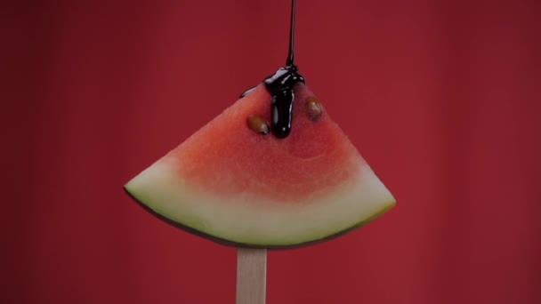 巧克力糖浆倒入成熟多汁的西瓜片 夏天的水果 鲜甜水果片 呈三角形 固定在红色背景的冰激凌棒上 — 图库视频影像