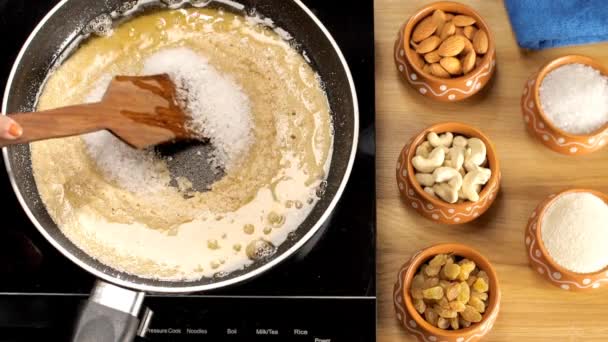 雌性的手把白糖和苏姬 苏米莉娜 哈尔瓦 布丁混合在一起一盘盛满了苏姬 哈尔瓦 Sooji Halwa 和干果及配料的烤盘 印度传统甜点 的布景 — 图库视频影像