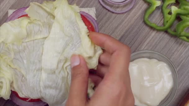 一个女孩把莴苣叶和面包片放在蔬菜三明治上 — 图库视频影像