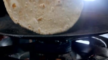 Yakın çekim - evdeki gaz sobasının üzerinde taze buğday kızılderili şapatisi yapmak. Ev aşçısının Hindistan 'da kahvaltı, öğle yemeği, akşam yemeği hazırlama sahnesi - pişirme konsepti