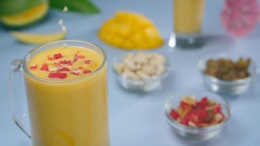 Ezilmiş fındık ezmesi lezzetli mango smoothie süsleme - Hindistan yaz içeceği. Sağlıklı Aam Lassi, kuru meyve ve tutti frutti 'li cam bardakların yakın çekimi.