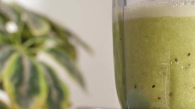 Beyaz arka planda şeffaf bir kabın içinde taze kivi meyve suyu. Bir blender içinde sallanan yeşil, ferahlatıcı meyve kokteylinin aşırı yakın görüntüsü - sağlıklı ve besleyici içecek konsepti