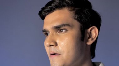 Temiz tıraşlı sağlıklı bir gencin antrenmandan sonra terlemesi. Yorgun bir sporcunun renkli bir arka plana karşı iç mekanda durduğu aşırı yakın çekim - fitness aktivitesi 