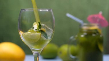 Hindistan 'da Aam Panna, yaz içeceği, nane yapraklı ve limon dilimli şeffaf bardakta Kairi Panna. Yakın planda cam bir kavanozun kokteyl şemsiyesiyle süslenmiş taze meyve suyu ve bulanık bir arka planda mango.