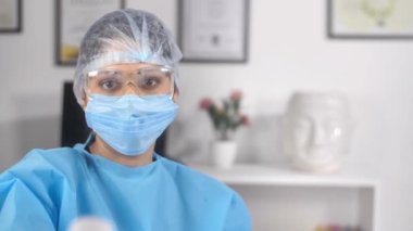 Kişisel koruyucu giysi (PPE Kit) giymiş bir sağlık görevlisi elinde kızılötesi termometre tutuyor. Coronavirus salgınının ortasında hastanede dijital / kızılötesi termometreyi işaret eden bir tıp uzmanının yakın plan fotoğrafı.