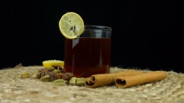 Dönüşümlü yeşil çay fincanı. Limon dilimiyle süslenmiş. Paspasın üstünde duruyor. Farklı Hint baharatları, tarçın, kakule ve yıldız anason içeren aromatik bir fincan limon çayının yakın görüntüsü.