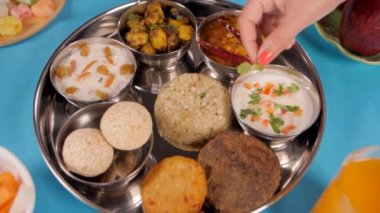 Yeni pişmiş Sabudana Khichdi 'nin üzerinde nane yaprakları tutan kadının eli. Geleneksel Kuzey Hindistan Vrat Thali Hindu festivallerinde çeşitli vejetaryen yiyeceklerle hazırlandı