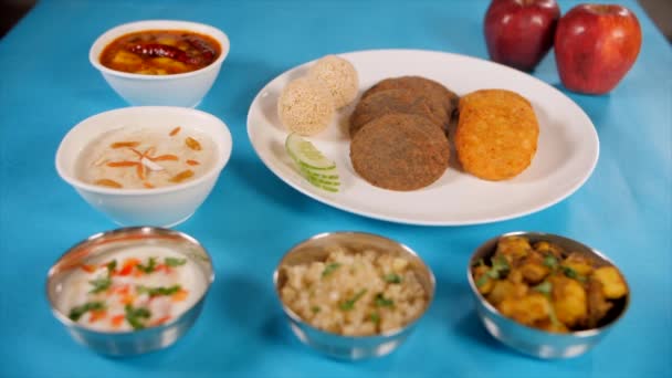 青い表面に配置された美しくメッキNavratri食品プレートのショットでズーム 宗教上の混乱 断食の日の間にヒンドゥスで提供されるインド料理の伝統的なタリーの閉鎖ショット — ストック動画
