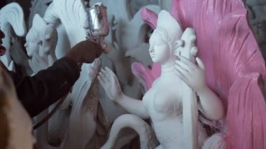 Profesyonel bir zanaatkarın, Tanrıça Saraswati 'nin heykeli olan Hint Festivali' ni resmetmesi. Hintli bir sanatçının, Saraswati Puja için püskürtücü bir aletle Hint idolü Ma Saraswati 'nin heykelini boyaması.