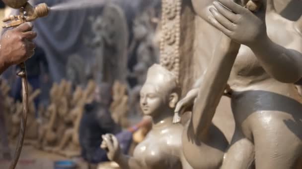 ヒンズー教の女神サラスワティの粘土彫刻を作るインドのアーティストの手 サラスワティ法会のための馬サラスワティの像に塗料を噴霧プロの職人の傾きのショット — ストック動画