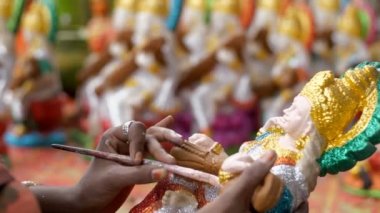 Hindu tanrıçasının kilden heykelini yapan kadın sanatçı. Sanatçı, Hindu tanrıça idolü / murti 'nin boyamasını bitiriyor. Arka planda Saraswati puja' nın diğer heykelleri de hazır.