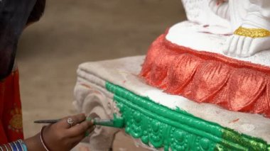 Hintli bir kadın sanatçının elleri bir Hindu tanrıçasının kilden heykelini boyuyor. Kadın kil ustası Saraswati puja / Hindu festivali için bir Hint tanrıçasının tasarımlarını çiziyor.