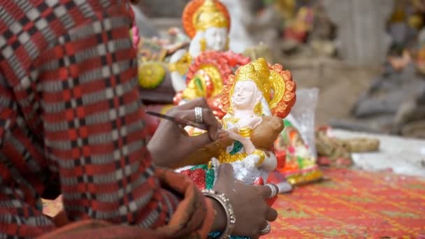 粘土艺术家在马萨拉斯瓦蒂的小雕像上涂上闪光的色彩作为最后的修饰 印度手工艺者为庆祝Saraswati Puja而为印度教女神的手上色 一个印度节日的概念 — 图库视频影像