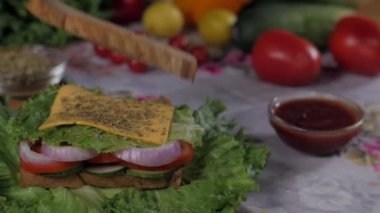 Sağlıklı kahverengi ekmek dilimi vejetaryen lezzetli bir kulüp sandviçi hazırlamak için düşüyor. Kırmızı kiraz domatesleri, sulu limonlar, yeşil kapsiyum ve ahşap bir masada marul yaprakları. 