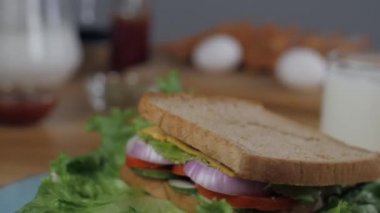 Lezzetli ızgara vejetaryen sandviçi döner döner döner döner bir pikapta - sabah kahvaltısı. Bir bardak saf süt, yumurta ve beyaz ekmek dilimlerinin yakın plan çekimi bulanık bir arkaplanda.