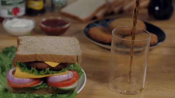 冷たい飲み物は 健康的な菜食主義のサンドイッチで提供されるためにクリアガラスに注ぐ 白いパンのスライス クリーミーなマヨネーズ トマトソースを木製のテーブルの上にまとめました — ストック動画