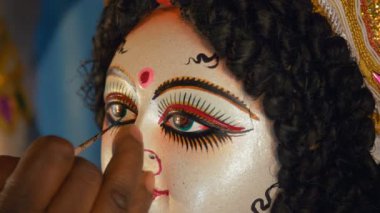 Bir zanaatkar Tanrıça Durga 'nın heykelinin gözlerine son rötuşları yapıyor. Hintli bir sanatçının Durga Puja festivali için Hint Tanrısı Ma Durga 'nın kil putunun gözlerini boyadığı yakın plan.
