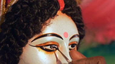 Hintli bir ressamın elleri. Ma Durga heykelinin gözlerini çiziyor. Durga Puja festivali için Tanrıça Durga 'nın kil heykelinin gözlerini boyayan bir zanaatkarın yakın çekimi.