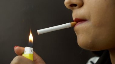 Yakın çekim - Hintli bir kadın zehirli bir sigara yakıyor ve sigara içiyor. Bağımlı bir genç kızın sigara tüttürürken ve duman üflerken yan görüntüsü. Sağlıksız bir yaşam tarzı. 
