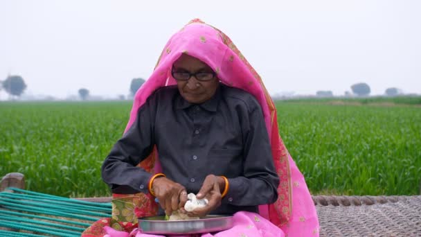 一名妇女在烹调之前 将花椰菜切成小块的中镜头 一位老太太穿着传统衣服 用传统的菜刀在编织的小床上切蔬菜 — 图库视频影像