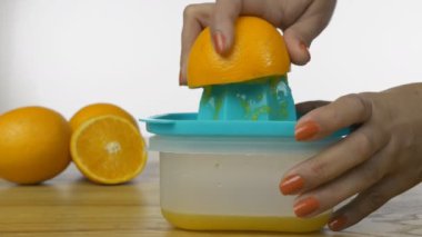 Kadın ellerinin el sıkacağı ile taze portakal suyu sıktığı yakın plan bir çekim. Beyaz arka planda elle sıkma makinesiyle portakal suyu sıkan Hintli bir kadının elleri.