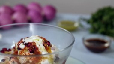 Aloo Tikki kasesi Chana, Dahi ile dekore edilmiş, bir döner tablada dönen nar, Hindistan 'dan gelen sokak yemekleri. Tam çiğ soğan, bir kase Chutney 's ve bulanık arka planda taze nane yaprakları.