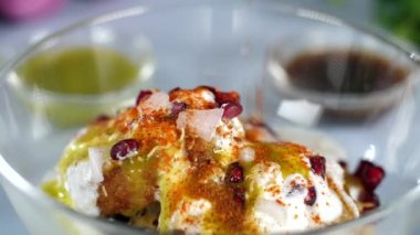 Eller kavrulmuş Masala 'yı bir kase Tikkis, nar ve Dahi' nin Hindistan 'dan getirdiği sokak yemeklerine koyuyor. Tam çiğ soğan, bir kase Chutney ve taze nane yaprakları bulanık bir arka planda bir arada tutulur.