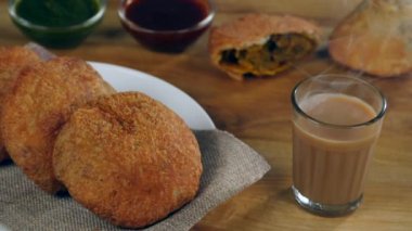 Çıtır Kachodis kahvaltı / akşam atıştırmalıkları için bir bardak sıcak çay servis etti. Yarısı yenmiş bir Kachori ve bir kase Chutney 'in yakın plan fotoğrafı. Ünlü Hint sokak yemekleri.