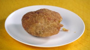Kuru bir Moong Dal Kachori 'nin, Hindistan' da seramik bir tabakta durduğu zaman aşımına uğramış fotoğrafı. Sarı ahşap bir masada tutulan ünlü Hint sokak yemeklerini yakından çek. Lezzetli yemekler.