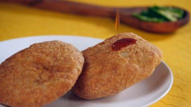 Tatlı tamarind Chutney / Saunth tabakta tutulan iki Kachori 'nin üzerine düşüyor - Sabah kahvaltısı Kuzey Hindistan. Pyaz Kachori - Hindistan Sokak Yemekleri 