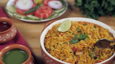 Kadının eli yavaş pişmiş vejetaryen Paneer Pulao 'yu kaşıkla tadıyor. İki turşu, sağlıklı salata ve vejetaryen Biryani 'li yeşil nane yaprağı.