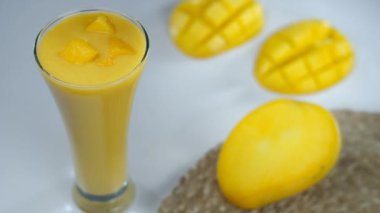 Taze nane yaprağıyla süslenmiş mango kokteyli. Yaz içeceği. Dilimlenmiş küp küp mangoların jüt minderde yakın plan çekimi. Lezzetli tropikal meyve.