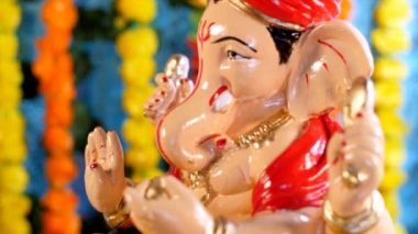 Lord Ganesha 'nın el yapımı kil heykeli. Hint Hindu festivali. Renkli çiçek arkaplanı. Yakından, turuncu ve sarı kadife çiçekleriyle süslenmiş Ganesha Lordu Murti 'nin altın rengi fotoğrafı. 