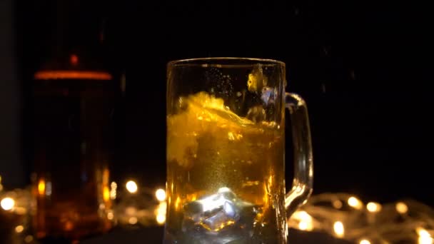 Великі Кубики Льоду Падають Прозору Склянку Пива Проти Сяючих Вогнів — стокове відео