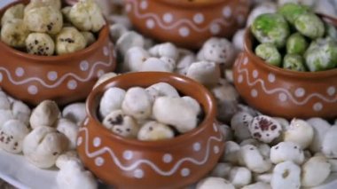 Beyaz nilüfer tohumu / Gordon Euryale seramik tabakta tutulan bir pikapta dönüyor. Peri-peri, Pudina, ve limon aromalı Makhanas toprakta güzelce saklanır - lezzetli bir aperatif, antioksidan, kilo kaybı, yaşlanma karşıtı özellikler