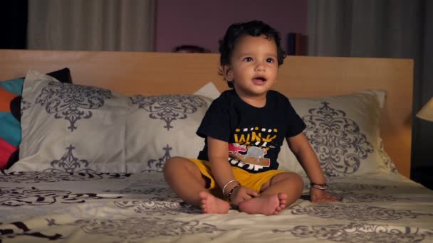 一个可爱的女孩摆姿势为相机 幼儿玩耍 一个快乐而兴奋的幼儿在床上爬行 探索着某种东西 核心稳定性 同步协调 — 图库视频影像